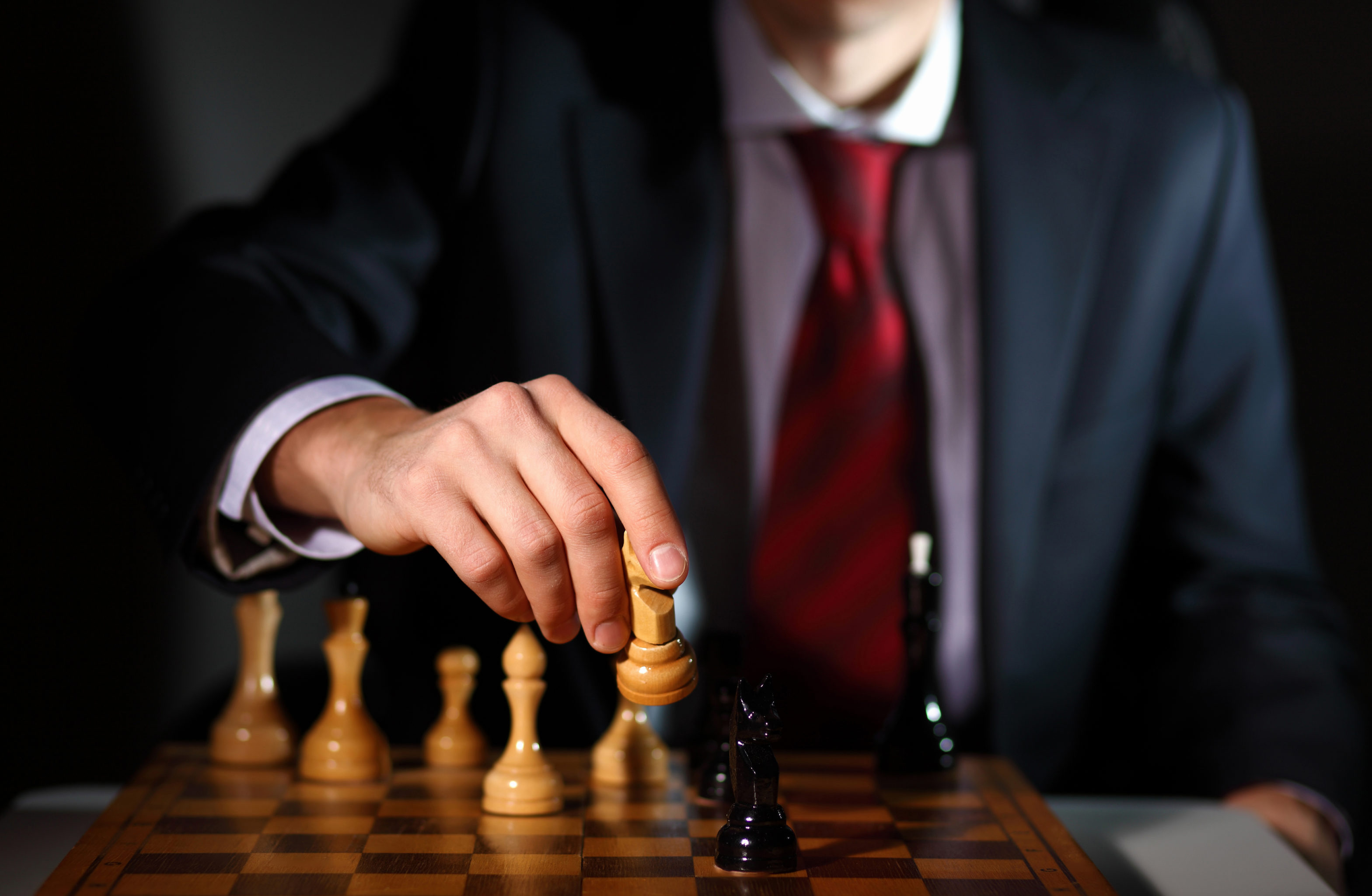 businessman playing chess wearing a suit and red tie