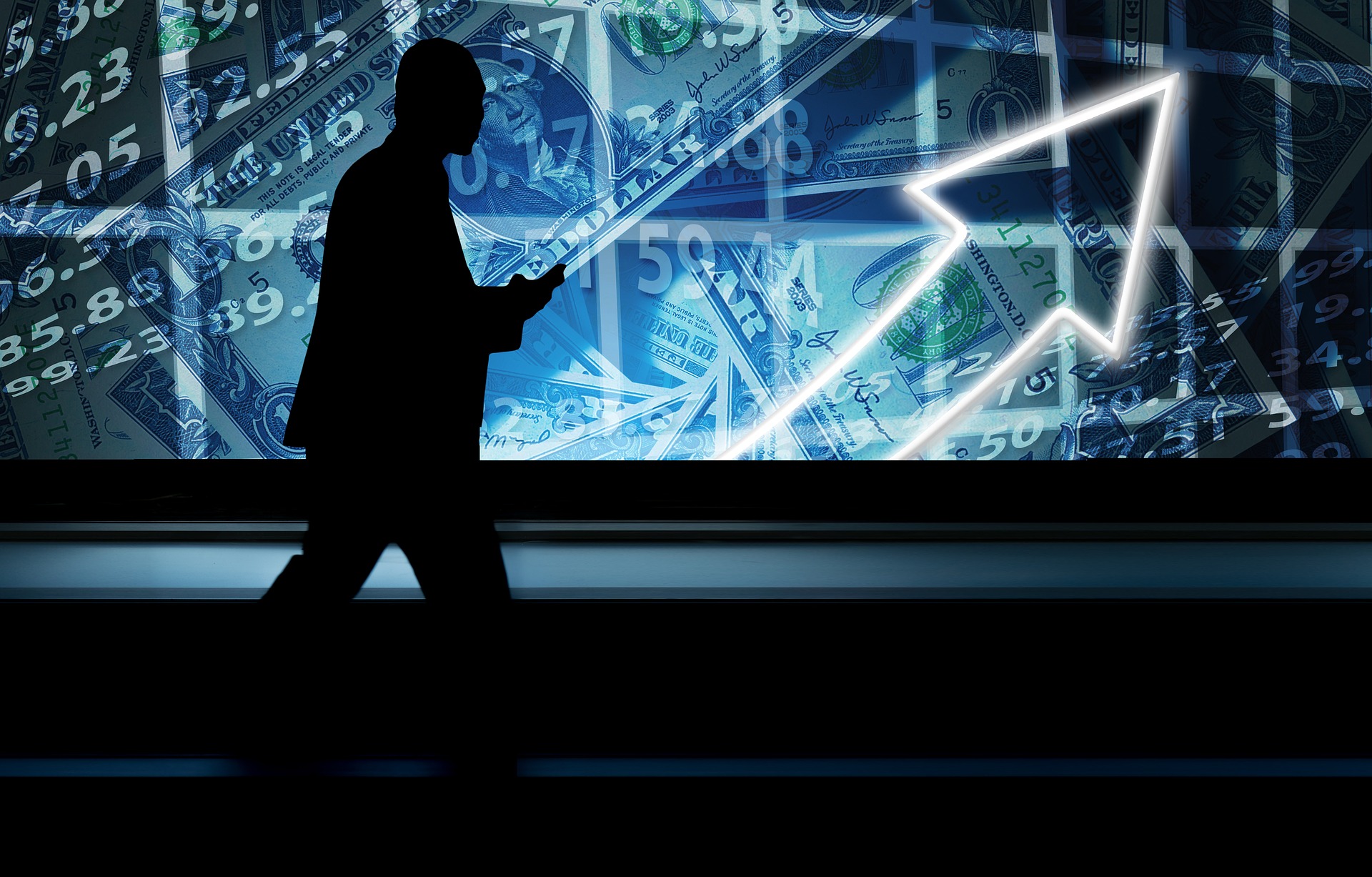 a silhouette of a businessman walking across a screen of financial indicators